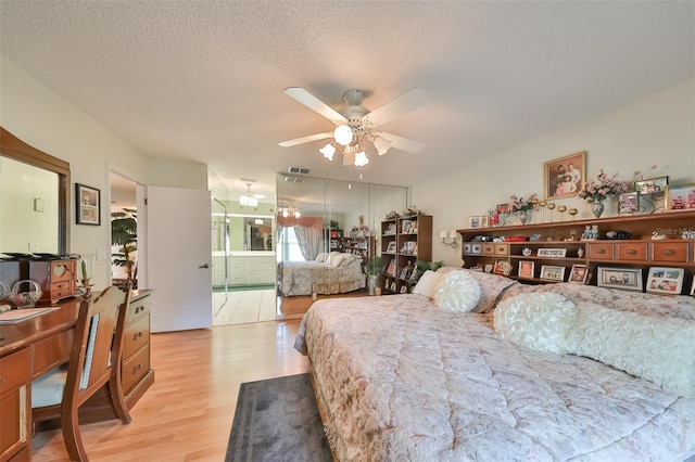 bedroom with a textured ceiling, ceiling fan, light hardwood / wood-style floors, and ensuite bathroom