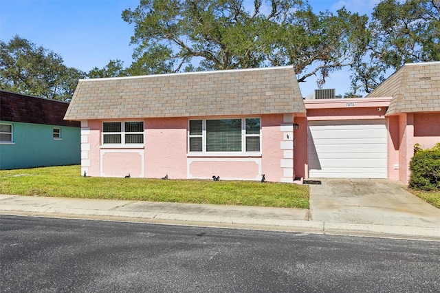 view of front of house with a shingled roof, mansard roof, and stucco siding