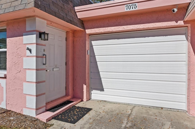 view of exterior entry with a garage and roof with shingles