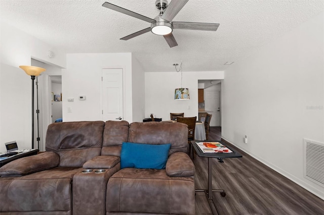 living room with ceiling fan, a textured ceiling, wood finished floors, visible vents, and baseboards