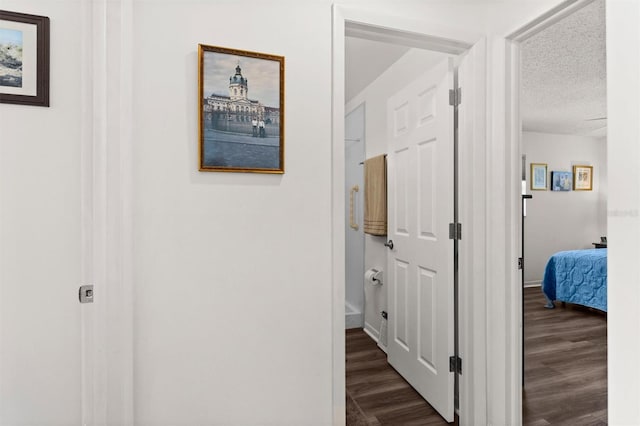 corridor featuring dark wood-style floors, a textured ceiling, and baseboards