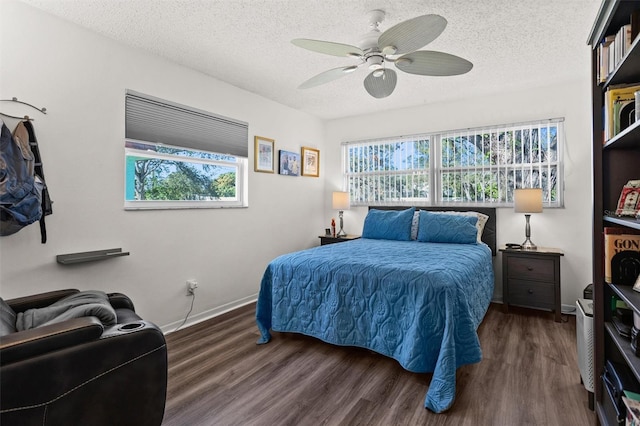 bedroom featuring a textured ceiling, multiple windows, baseboards, and wood finished floors