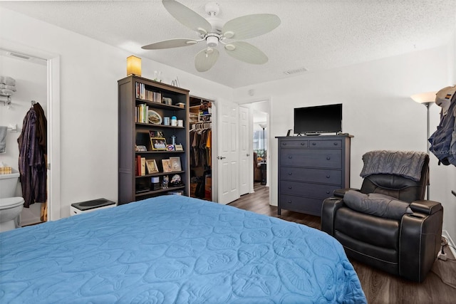 bedroom with a closet, visible vents, a spacious closet, dark wood-type flooring, and a textured ceiling