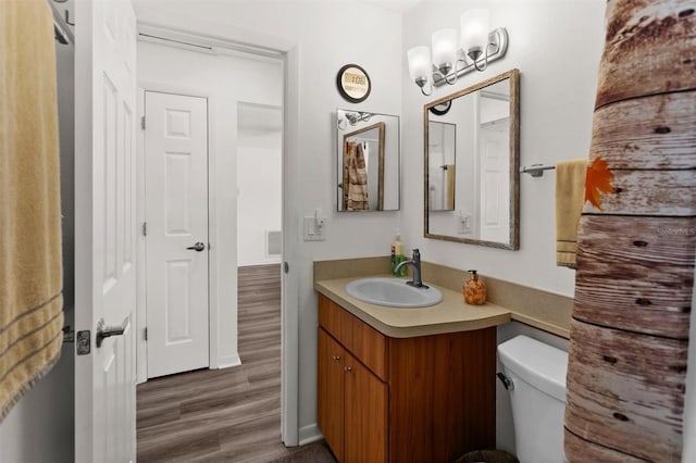 half bathroom featuring vanity, toilet, and wood finished floors