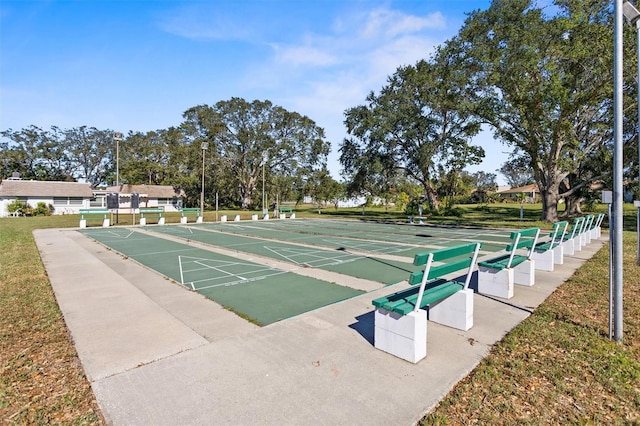 view of community with shuffleboard and a lawn