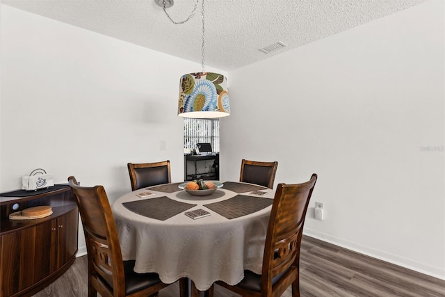 dining space with baseboards, a textured ceiling, visible vents, and wood finished floors