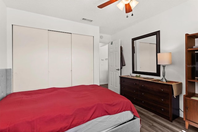 bedroom with a closet, visible vents, ceiling fan, a textured ceiling, and wood finished floors