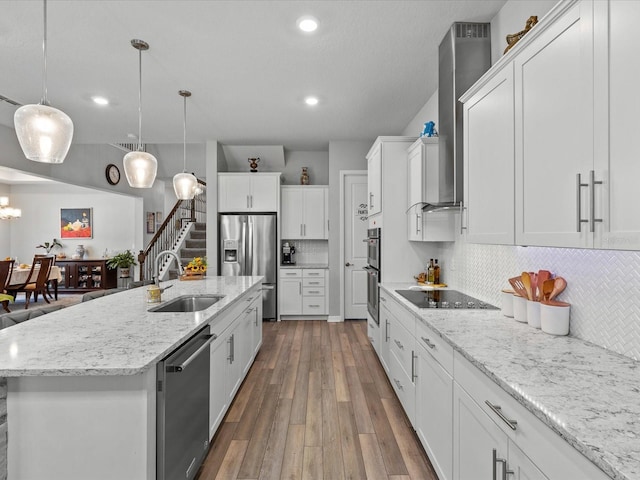 kitchen with white cabinetry, sink, hanging light fixtures, an island with sink, and appliances with stainless steel finishes