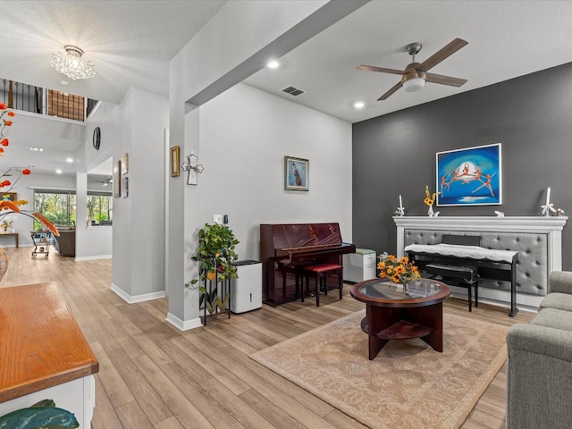 living room with a textured ceiling, wood-type flooring, and ceiling fan with notable chandelier