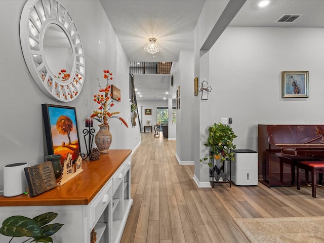 corridor with light hardwood / wood-style flooring and an inviting chandelier