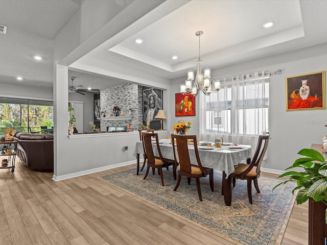 dining room featuring light hardwood / wood-style floors, a fireplace, and a tray ceiling