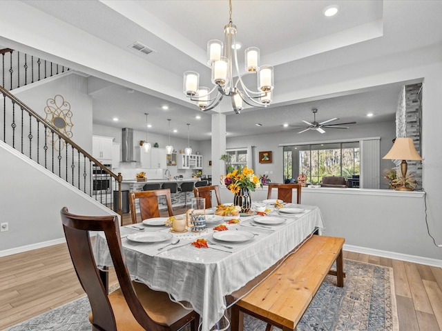 dining room with ceiling fan with notable chandelier and light hardwood / wood-style floors