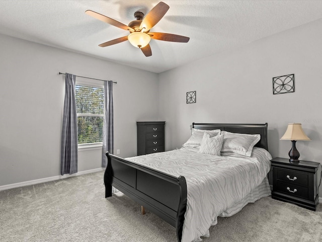 carpeted bedroom featuring ceiling fan and a textured ceiling