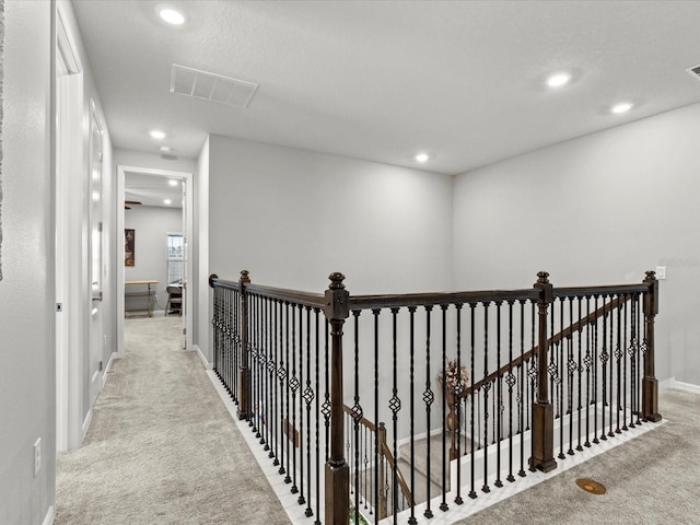 corridor with light carpet and a textured ceiling