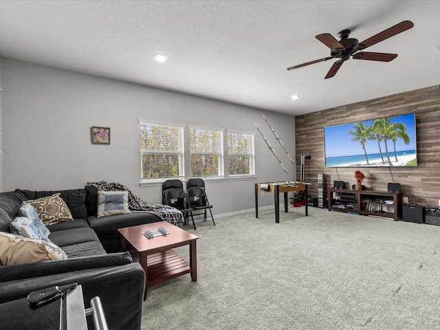 living room featuring a textured ceiling, carpet floors, ceiling fan, and wood walls