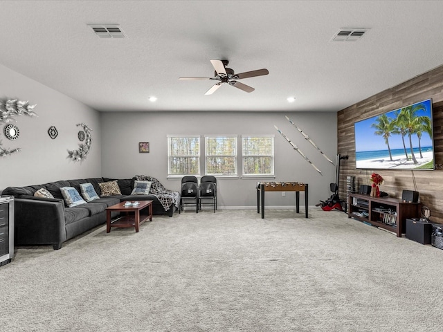 carpeted living room featuring ceiling fan, a textured ceiling, and wooden walls