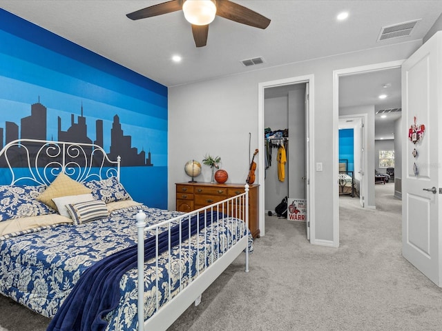 carpeted bedroom featuring ceiling fan, a walk in closet, and a closet