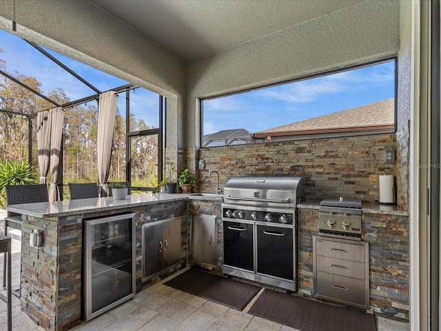 view of patio / terrace with an outdoor kitchen, area for grilling, an outdoor wet bar, glass enclosure, and wine cooler