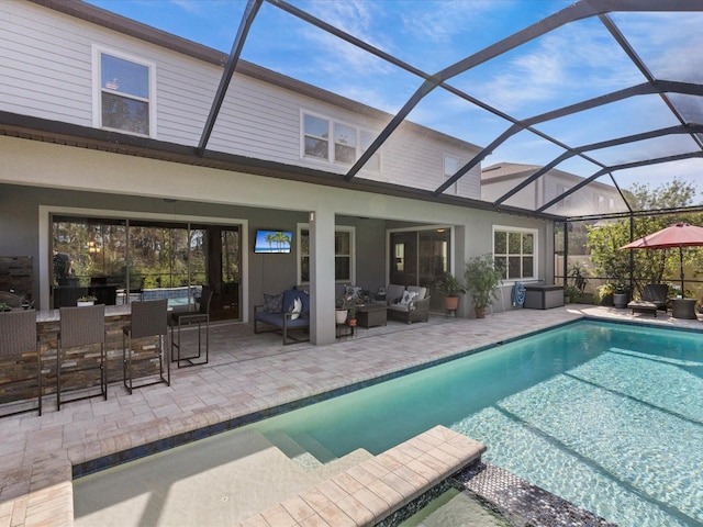 view of pool with outdoor lounge area, a bar, a patio, and glass enclosure