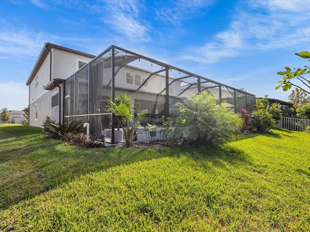 rear view of house featuring a lawn and glass enclosure