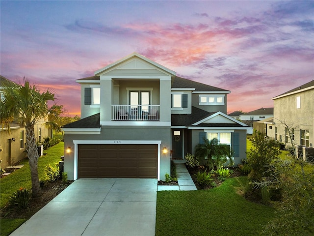 view of front of property featuring a lawn, a balcony, and a garage