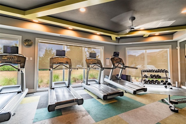 workout area with a tray ceiling and ceiling fan