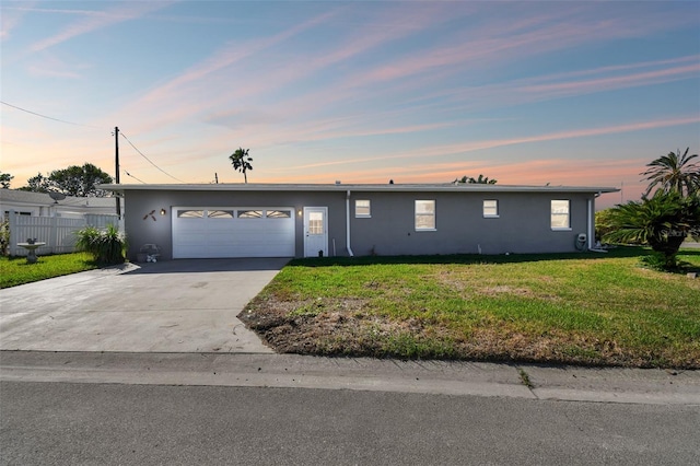 ranch-style house with stucco siding, a lawn, driveway, fence, and a garage