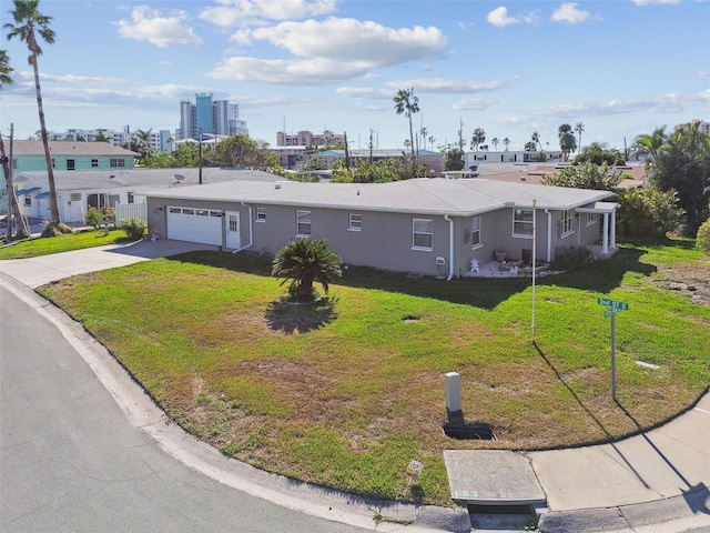 ranch-style home featuring an attached garage, stucco siding, concrete driveway, a front lawn, and a city view