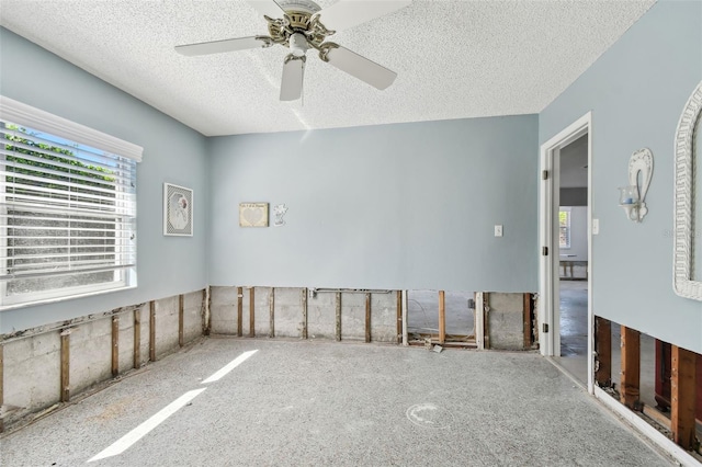 unfurnished room with ceiling fan and a textured ceiling