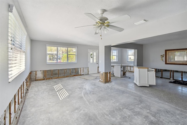 unfurnished living room featuring a textured ceiling, plenty of natural light, and ceiling fan