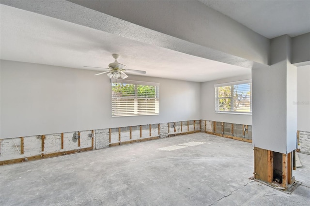 spare room with concrete flooring, a wealth of natural light, and ceiling fan