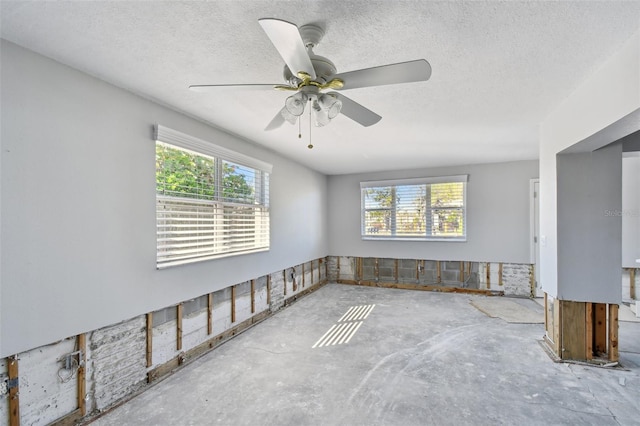 unfurnished room with plenty of natural light, a ceiling fan, and a textured ceiling