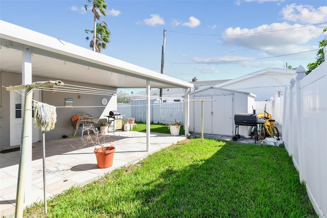 view of yard with a patio, a storage shed, an outbuilding, and fence