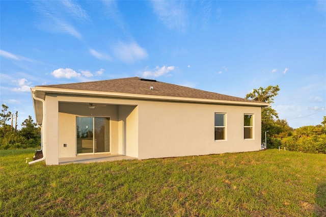 back of property featuring ceiling fan and a lawn