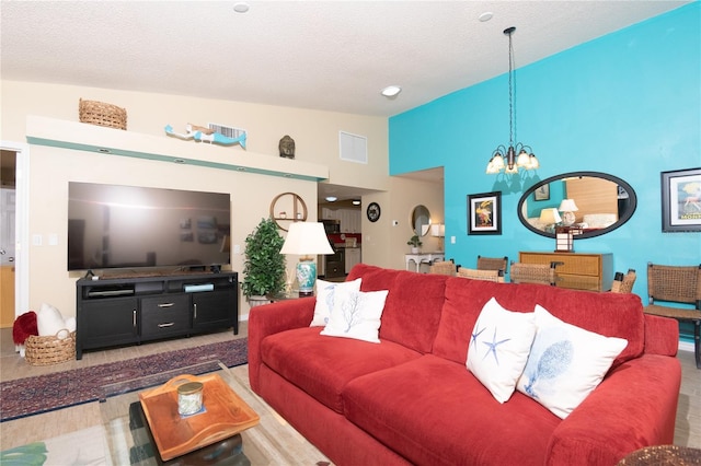 living room with vaulted ceiling, a textured ceiling, and an inviting chandelier