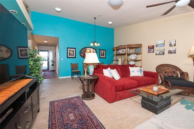 living room featuring ceiling fan with notable chandelier and a textured ceiling