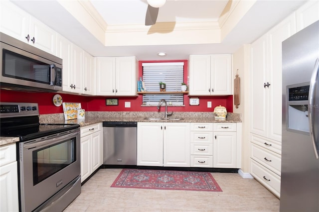 kitchen featuring stainless steel appliances, sink, white cabinets, and a tray ceiling