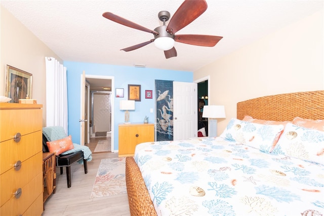 bedroom with ensuite bathroom, a textured ceiling, a closet, ceiling fan, and light hardwood / wood-style floors