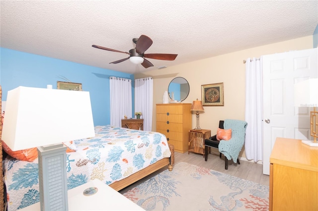 bedroom with ceiling fan, a textured ceiling, and light wood-type flooring