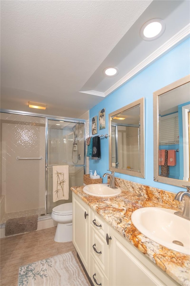 bathroom with crown molding, vanity, toilet, and a shower with shower door