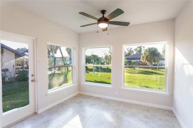 unfurnished sunroom with ceiling fan and a healthy amount of sunlight