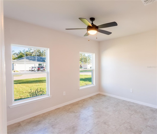 tiled empty room with a wealth of natural light and ceiling fan