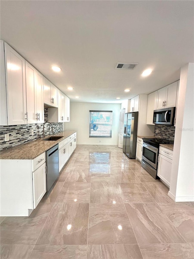 kitchen featuring white cabinets, stainless steel appliances, dark stone counters, and sink