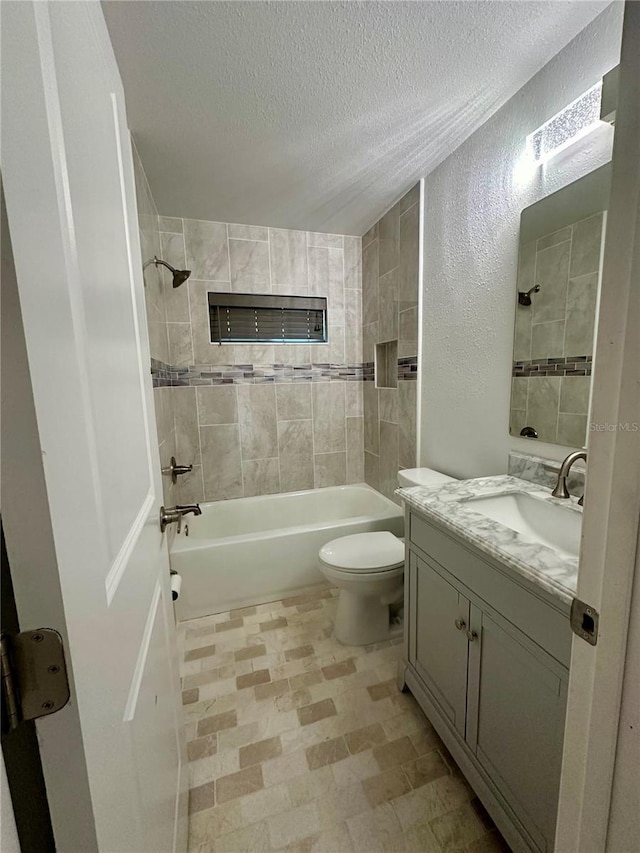 full bathroom featuring tiled shower / bath, vanity, a textured ceiling, and toilet