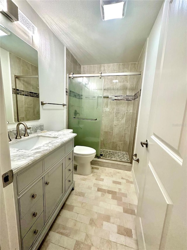 bathroom with a textured ceiling, vanity, toilet, and a shower with door