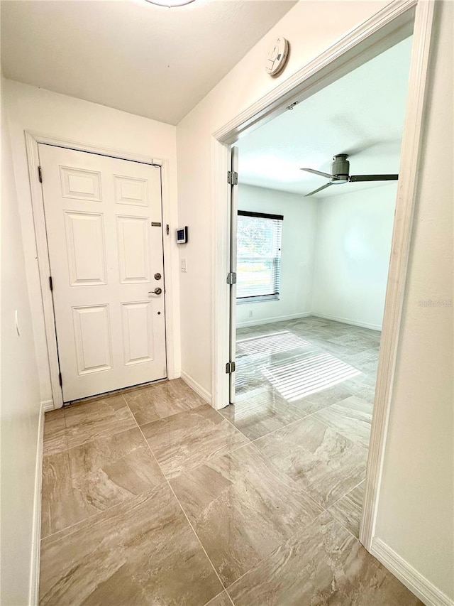 foyer entrance featuring ceiling fan and baseboards