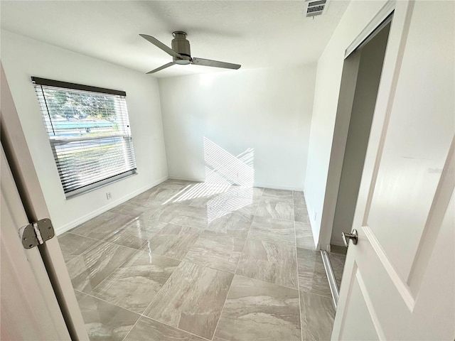 empty room with ceiling fan, visible vents, and baseboards