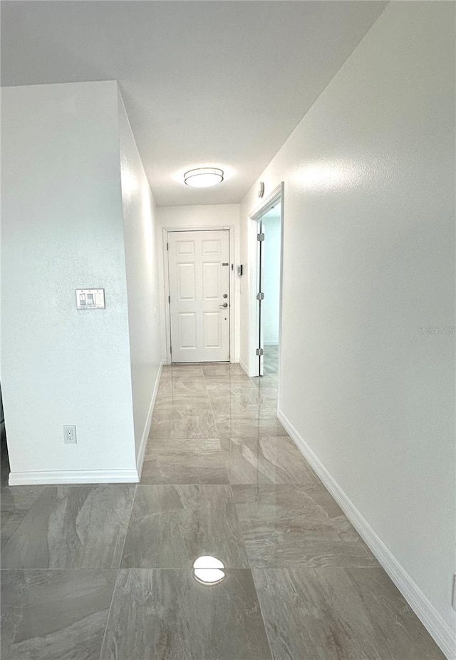 hall with marble finish floor and baseboards