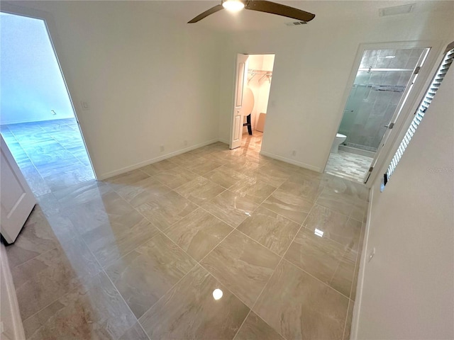 unfurnished bedroom featuring baseboards, a ceiling fan, ensuite bathroom, a spacious closet, and a closet