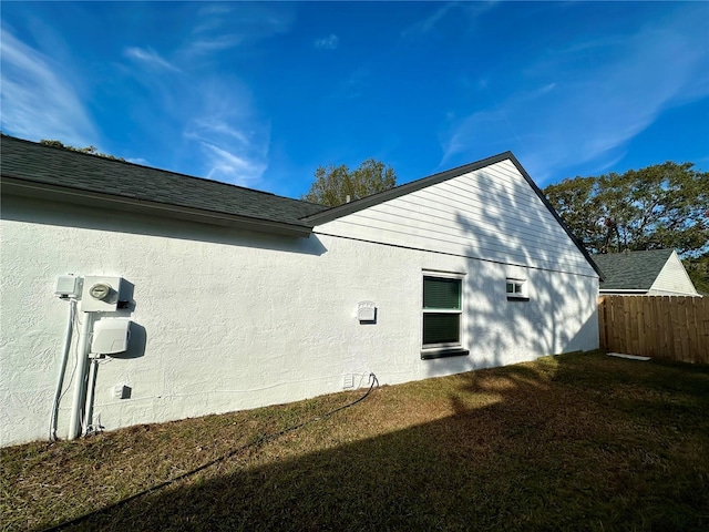 rear view of property featuring a yard, stucco siding, a shingled roof, crawl space, and fence